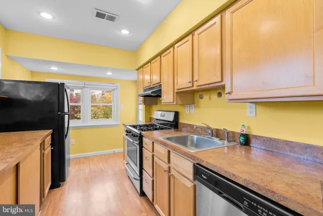 a kitchen with stainless steel appliances a sink a stove and a wooden floor