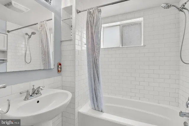 a bathroom with a white bath tub sitting next to a white sink and a mirror