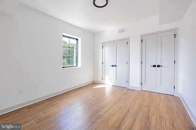 a view of an empty room with wooden floor and window