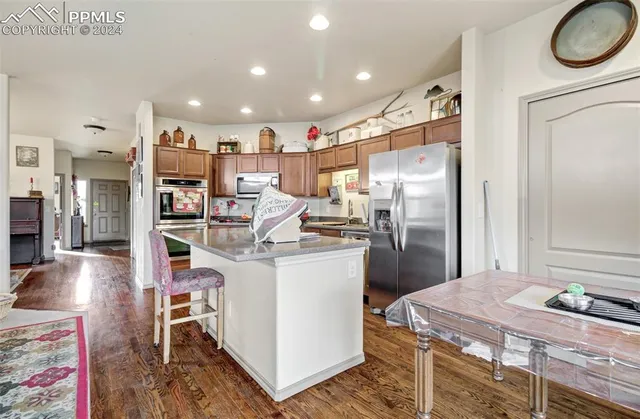 a kitchen with kitchen island a stove a refrigerator and a dining table with wooden floor