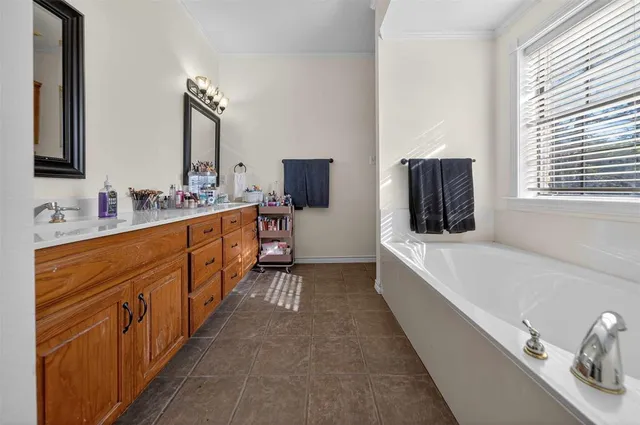 a large white bathroom with a double vanity sink a mirror and a bathtub