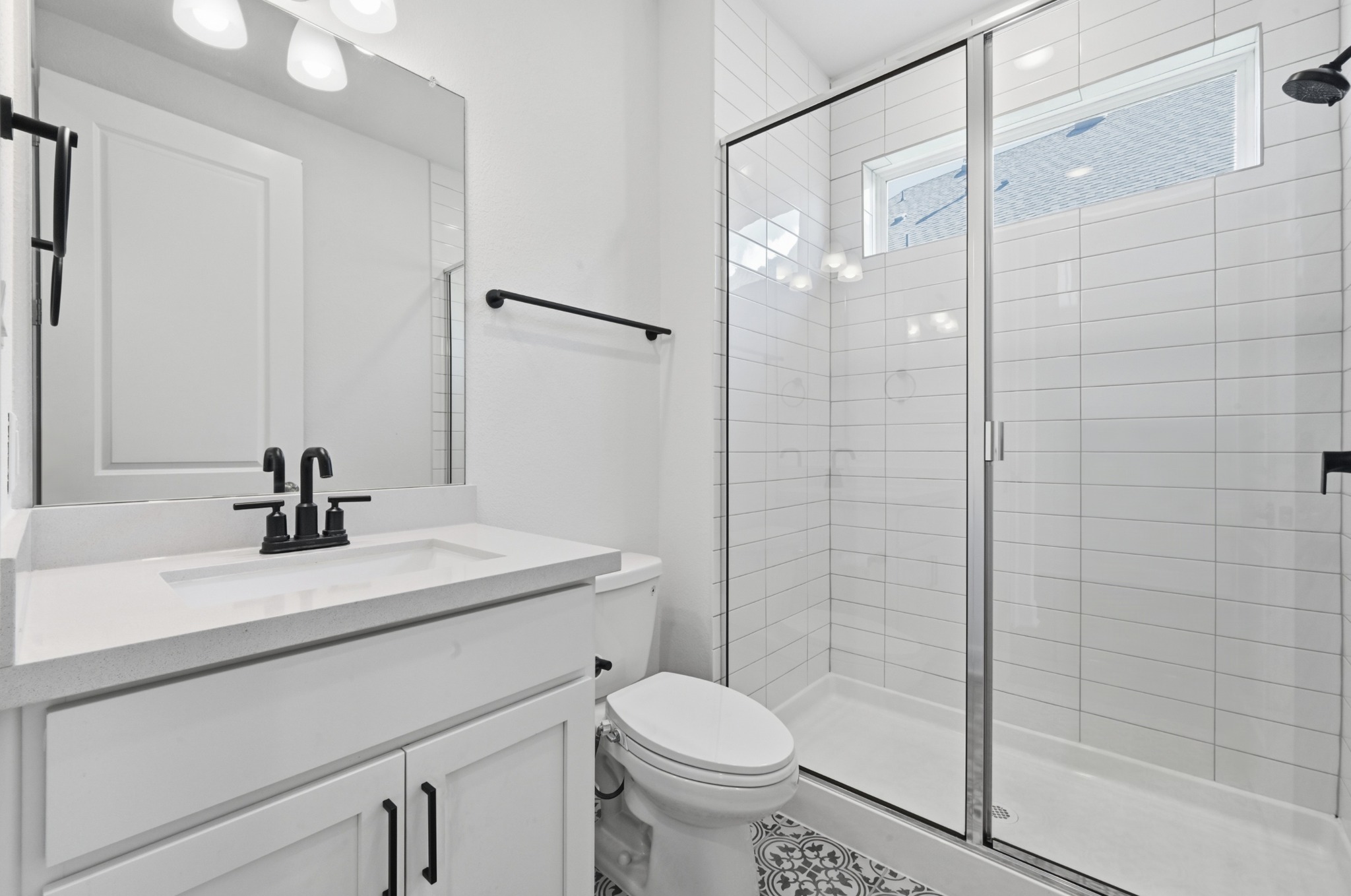 433 Running Bird Road Austin, TX 78737 - Photo 30 of 40 A well-lit bathroom presents a contemporary vanity, toilet, and glass-enclosed shower with white subway tile.