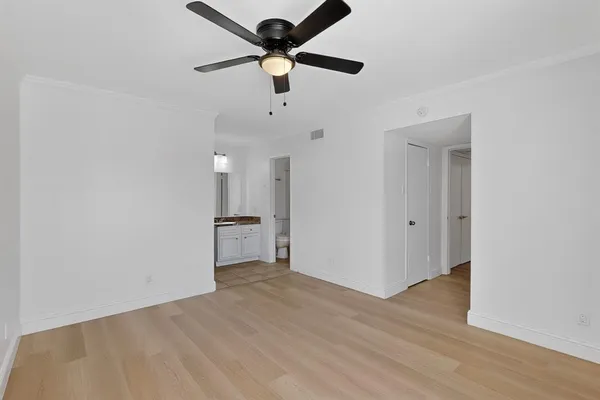 an empty room with wooden floor and a ceiling fan