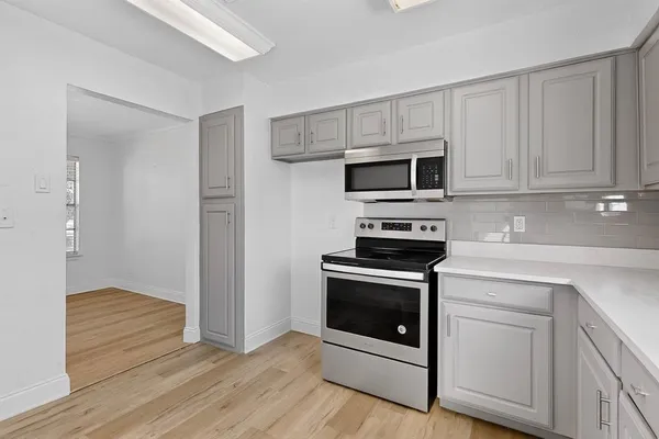 a kitchen with white cabinets stainless steel appliances and wooden floor
