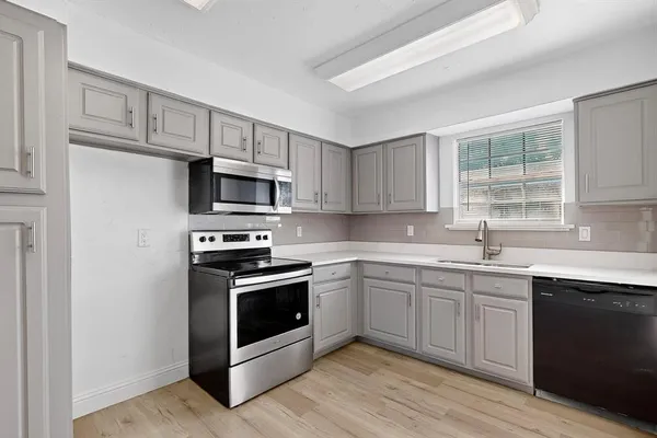 a kitchen with sink a microwave and cabinets