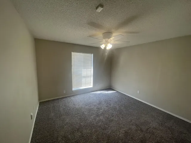 an empty room with windows and fan