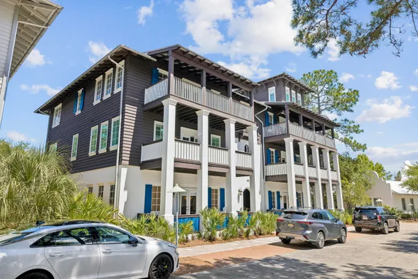 a front view of a building with lot of cars and trees