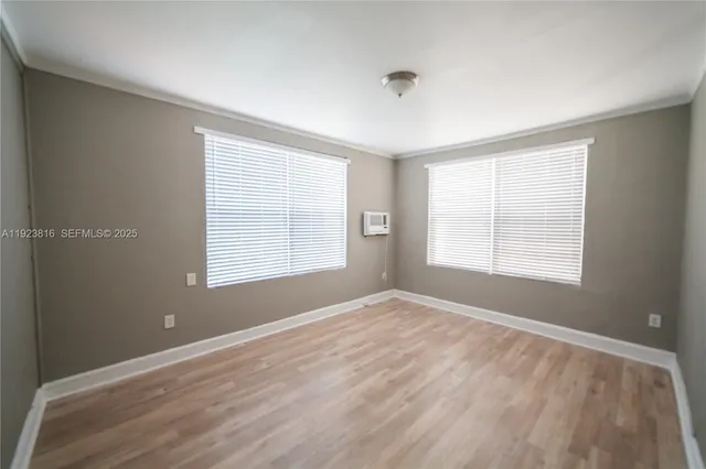 a view of an empty room with wooden floor and a window