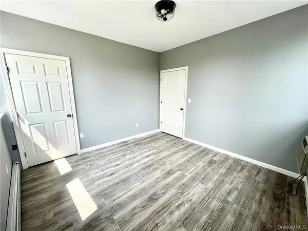 an empty room with wooden floor cabinet and windows