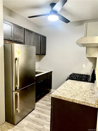 a kitchen with granite countertop a refrigerator a sink and cabinets