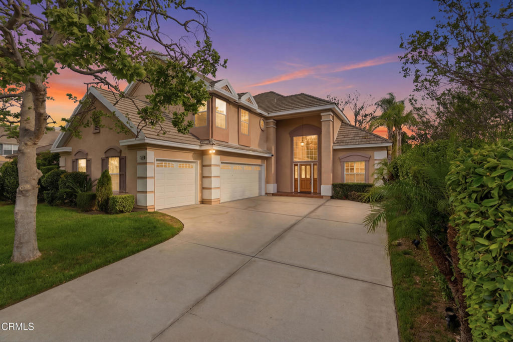 a front view of a house with a garden and a tree