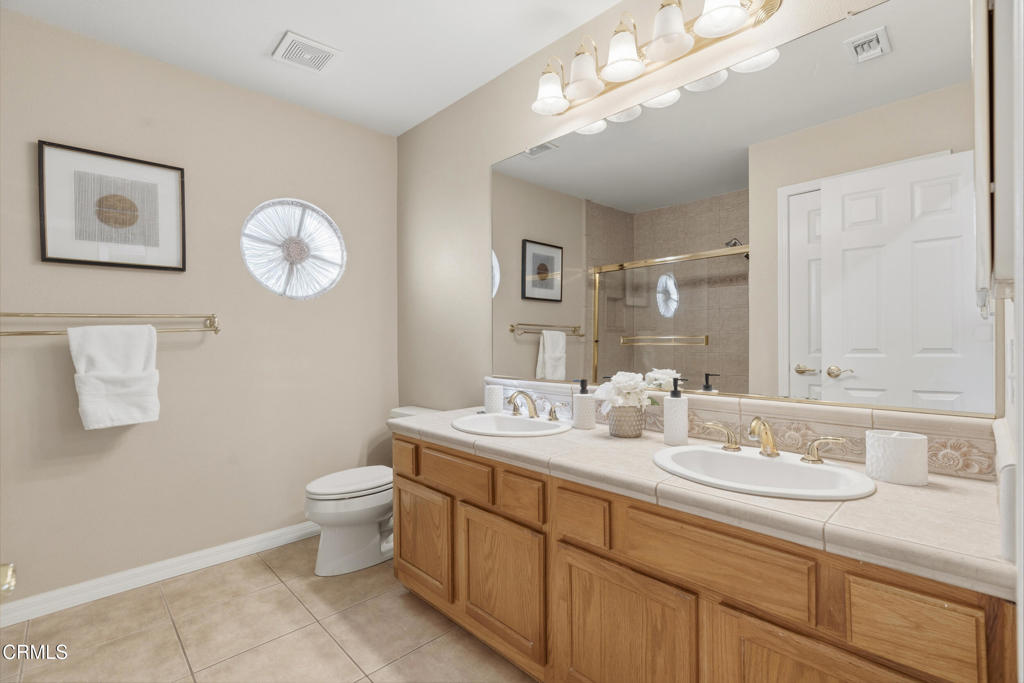 11543 Ragusa Drive Rancho Cucamonga, CA 91701 - Photo 37 of 69 a bathroom with a toilet a double vanity sink and a mirror