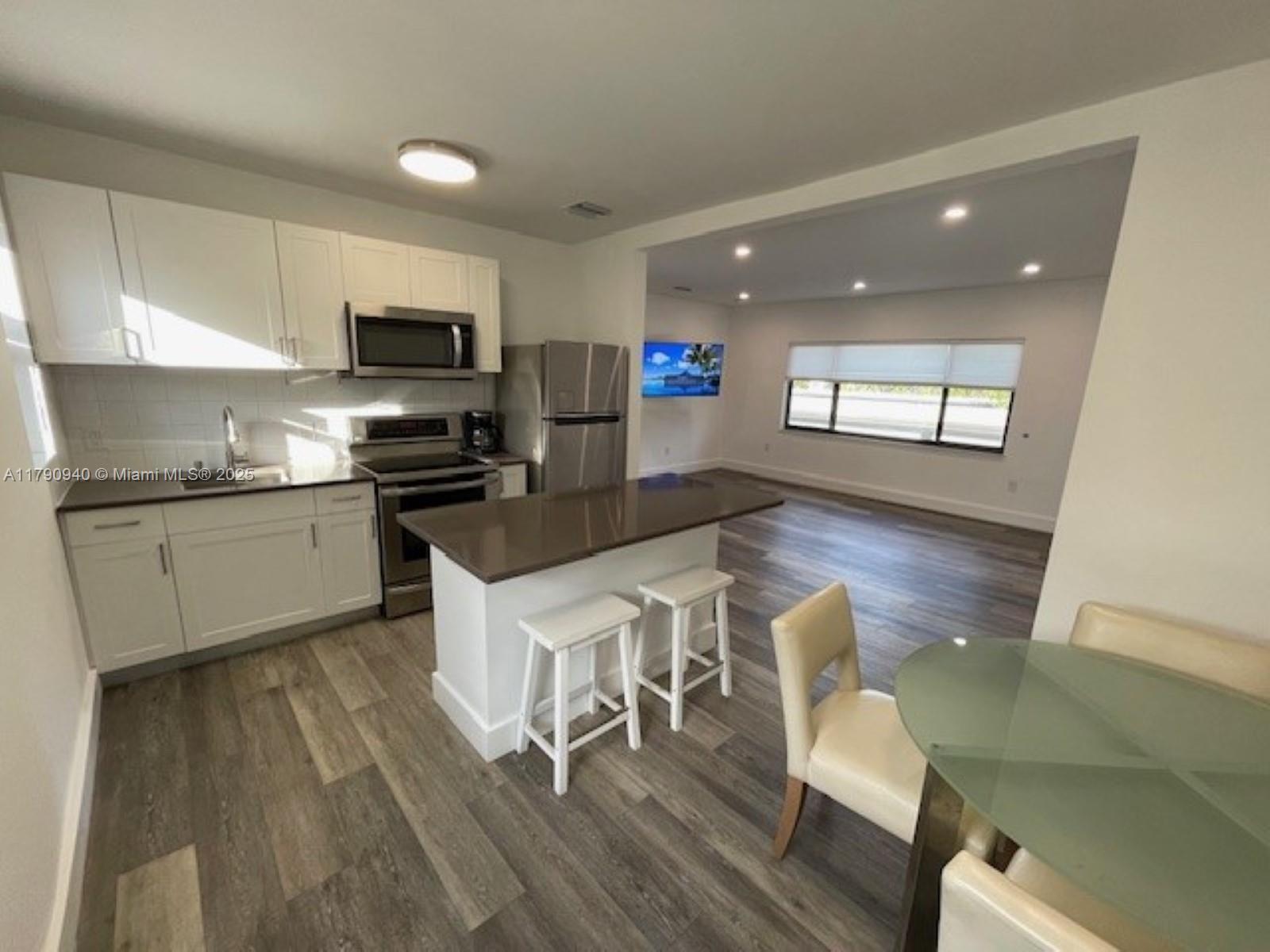 2141 Southwest 14th Terrace, Unit 4 Miami, FL 33145 - Photo 3 of 15 a kitchen with stainless steel appliances granite countertop a table chairs sink and cabinets