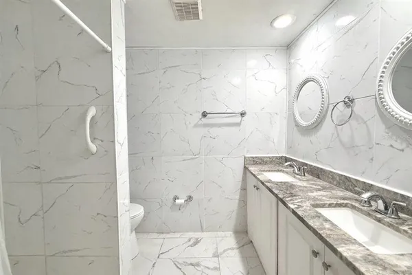 a bathroom with a granite countertop sink a toilet and a shower