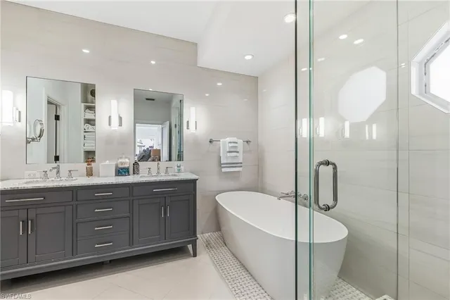 a bathroom with a tub a double vanity sink and mirror