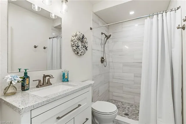 a bathroom with a granite countertop sink a toilet and shower