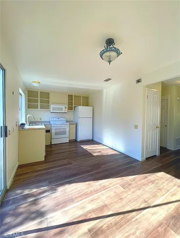 a view of a room with wooden floor kitchen view and a window