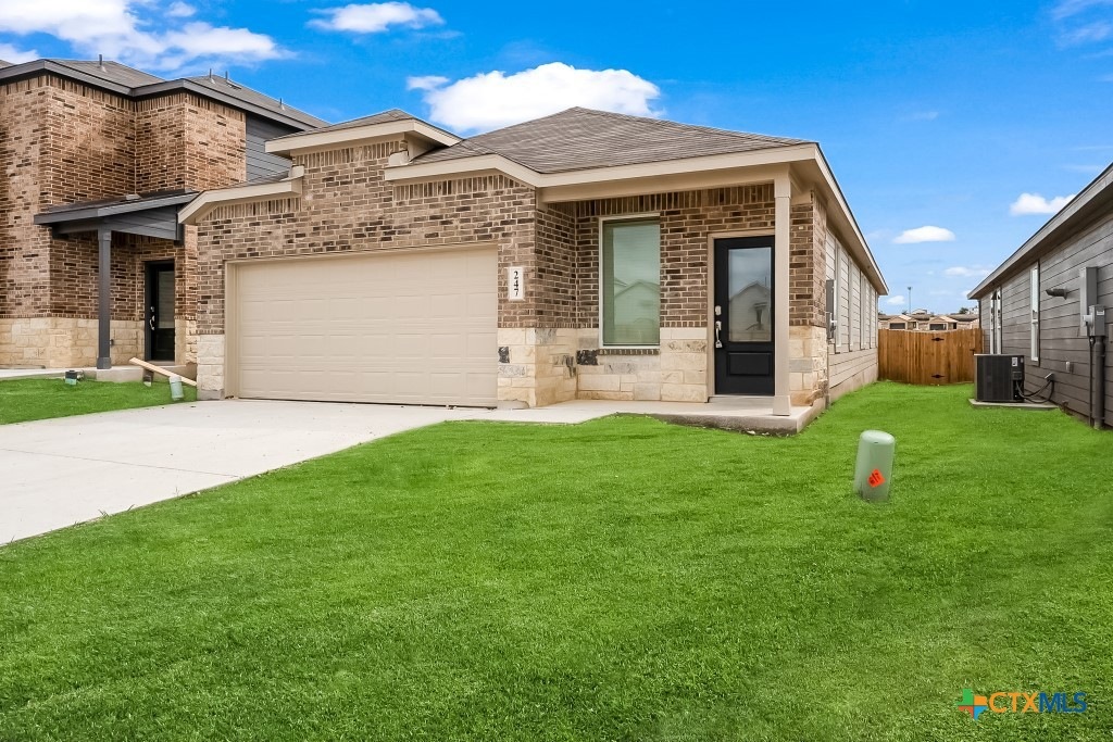 View of front of house featuring brick siding, concrete driveway, an attached garage, and stone siding
