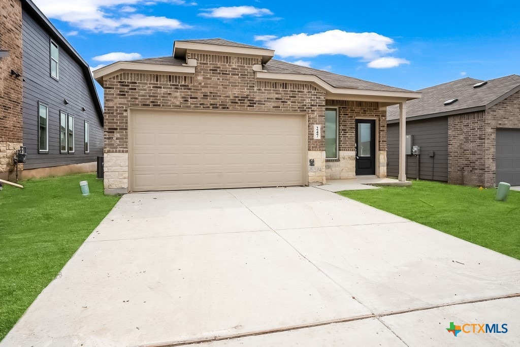 247 Flathead New Braunfels, TX 78130 - Photo 2 of 17 View of front facade featuring brick siding, a front yard, driveway, and an attached garage