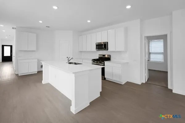 a view of kitchen with stainless steel appliances kitchen island sink stove and cabinets