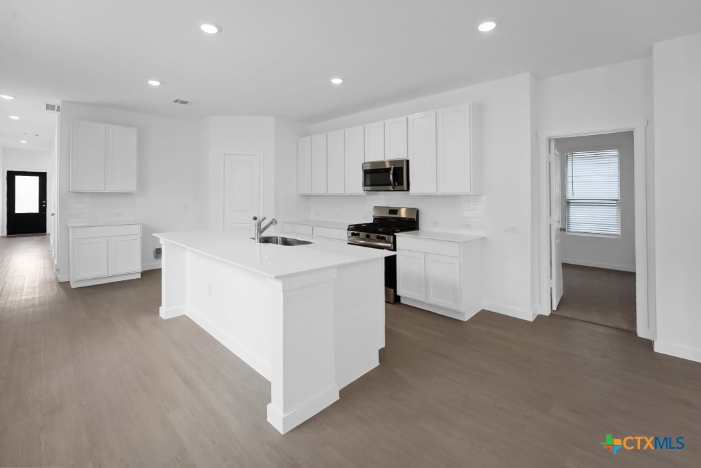 247 Flathead New Braunfels, TX 78130 - Photo 5 of 17 Kitchen with stainless steel appliances, white cabinetry, dark wood-type flooring, an island with sink, and recessed lighting