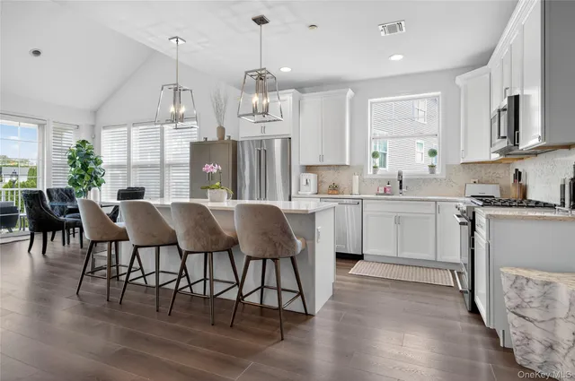 a large kitchen with cabinets chairs and wooden floor