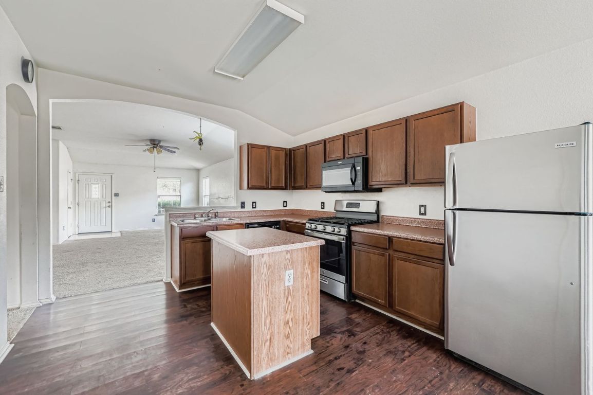 200 Firebush Way Buda, TX 78610 - Photo 12 of 29 a kitchen with a refrigerator a stove top oven a sink and dishwasher with wooden floor
