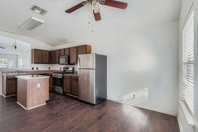 a kitchen with stainless steel appliances a refrigerator a stove a sink and a window