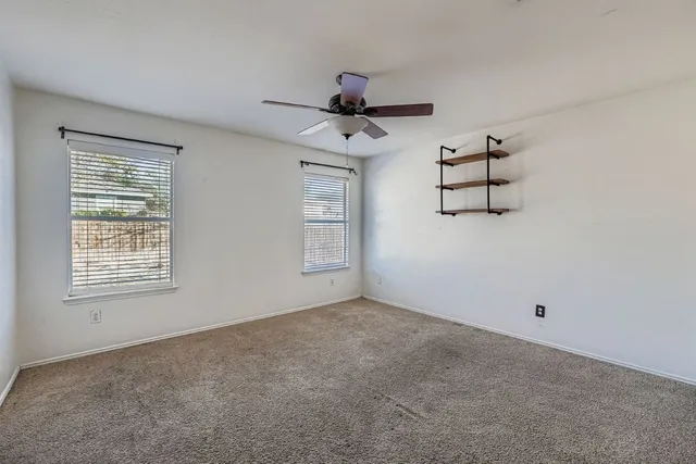 a view of room with ceiling fan and windows