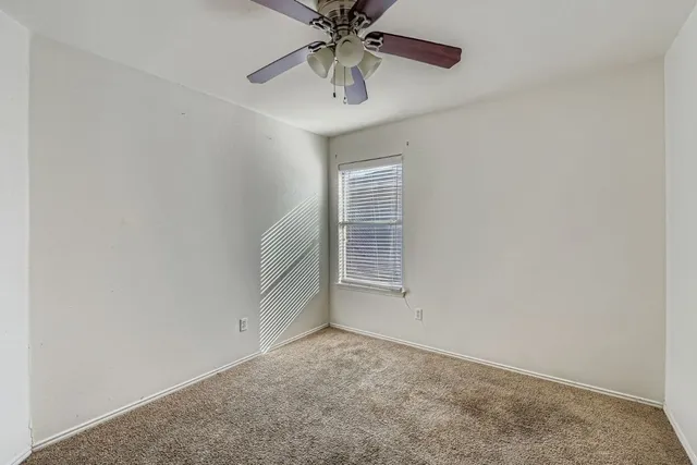 an empty room with chandelier fan and windows