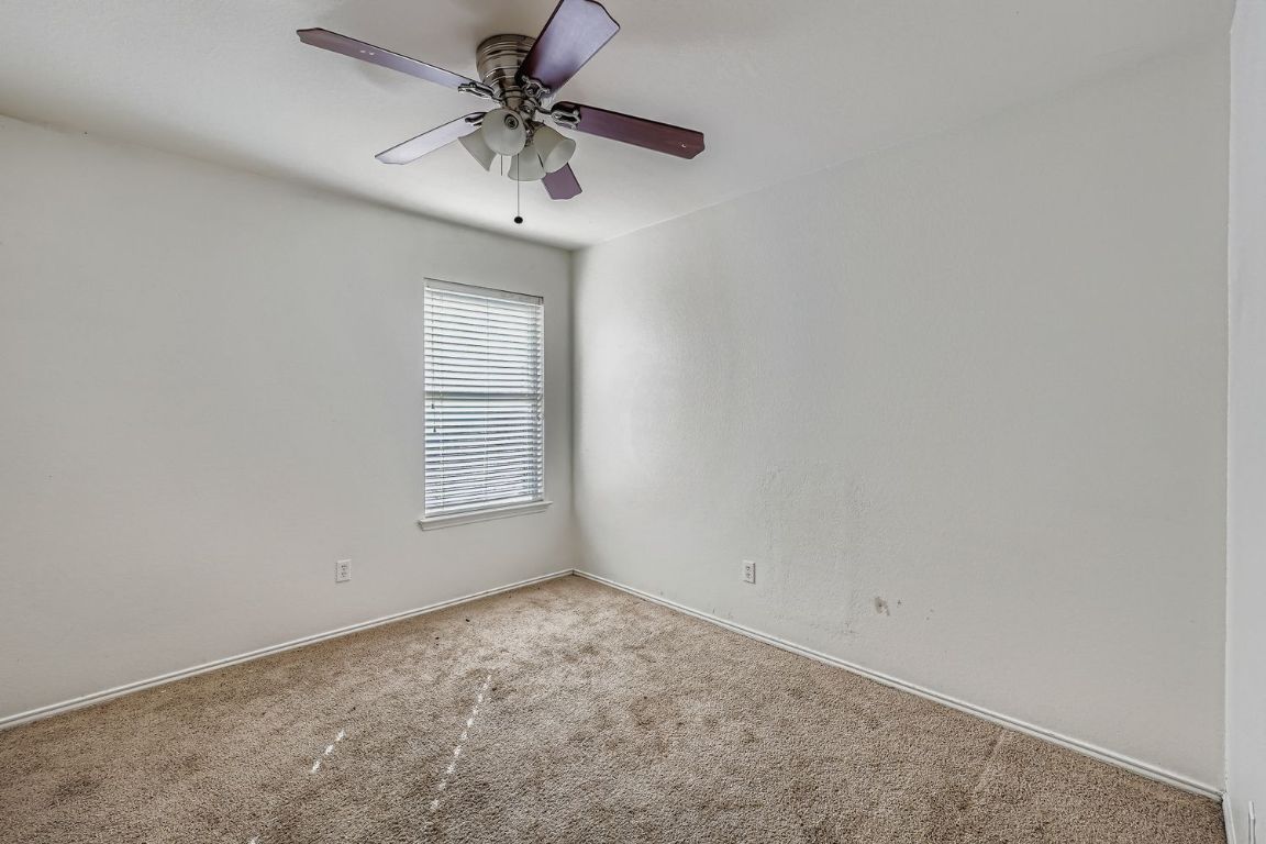 200 Firebush Way Buda, TX 78610 - Photo 22 of 29 an empty room with a chandelier fan and windows