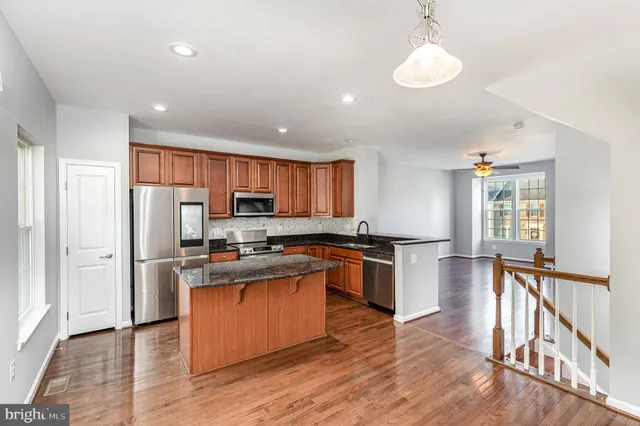 a kitchen with stainless steel appliances granite countertop a refrigerator a stove top oven a sink dishwasher and white cabinets with wooden floor