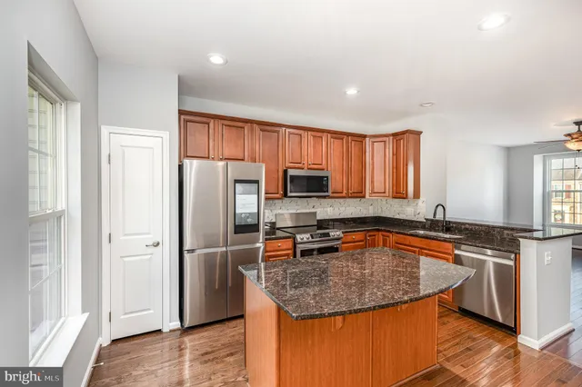 a kitchen with stainless steel appliances granite countertop a refrigerator a sink a stove a microwave and wooden cabinets