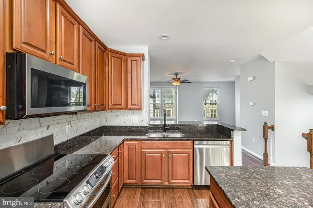 a kitchen with granite countertop a stove a sink and a microwave
