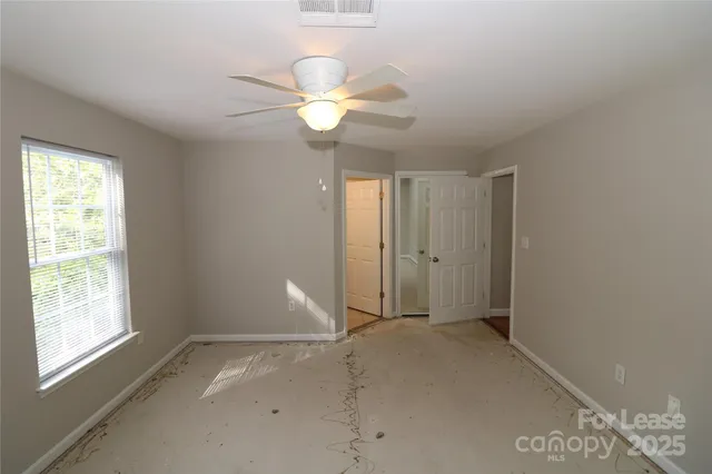 a view of an empty room with window and chandelier fan