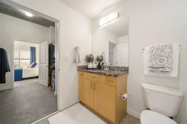 a bathroom with a granite countertop toilet sink and mirror