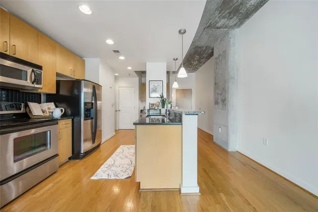 a kitchen with stainless steel appliances granite countertop a refrigerator a stove and a wooden floors