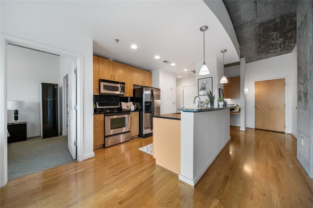 250 Pharr Road Northeast, Unit 412 Atlanta, GA 30305 - Photo 3 of 49 a kitchen with stainless steel appliances kitchen island granite countertop a stove top oven a refrigerator and a sink