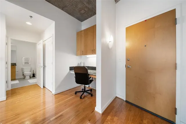 a view of a hallway with wooden floor and a bathroom