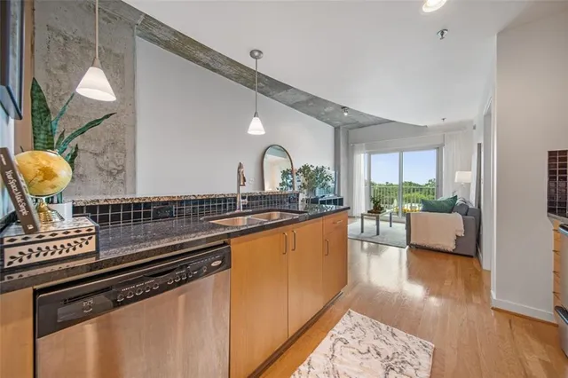 a open kitchen with stainless steel appliances granite countertop a sink dishwasher a stove a dining table and chairs with wooden floor