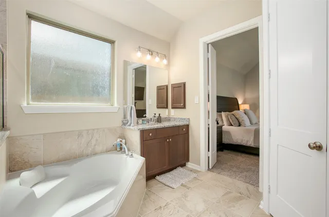 a en suite spacious bathroom with a granite countertop tub mirror and double vanity