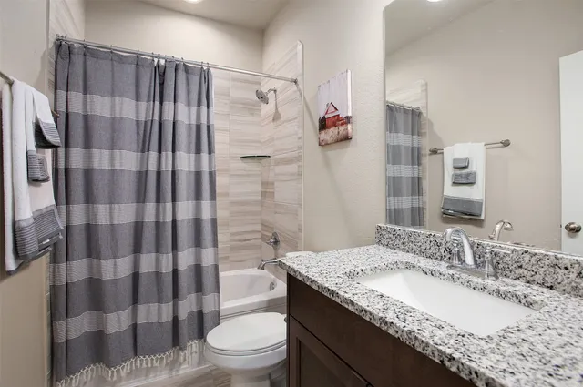 a bathroom with a granite countertop sink toilet and shower