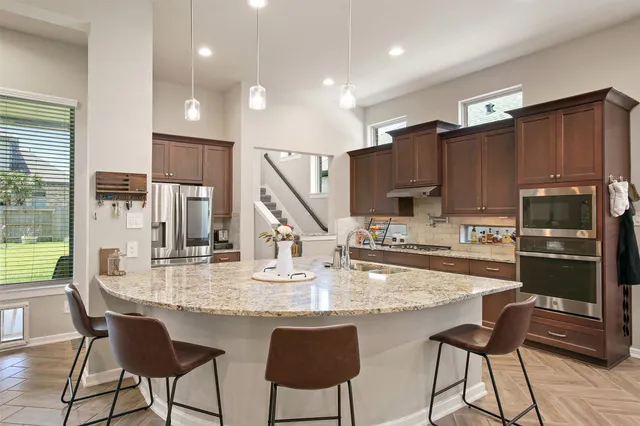 a kitchen with stainless steel appliances granite countertop a stove top oven a refrigerator and kitchen island
