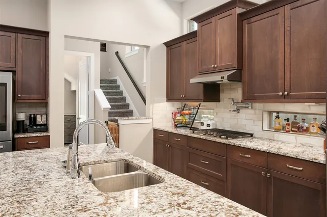 a kitchen with stainless steel appliances kitchen island granite countertop a sink refrigerator and cabinets
