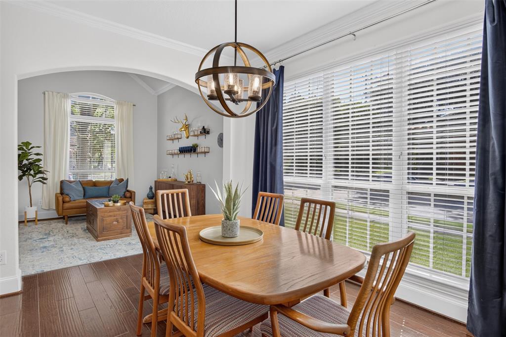 842 Sun Meadow Road Allen, TX 75013 - Photo 12 of 39 Dining area featuring wood-finish flooring, a contemporary chandelier, and large windows with blinds