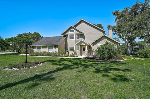 a view of a white house with a big yard and large trees