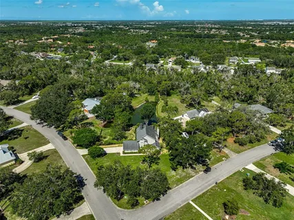 an aerial view of a residential houses with outdoor space and trees