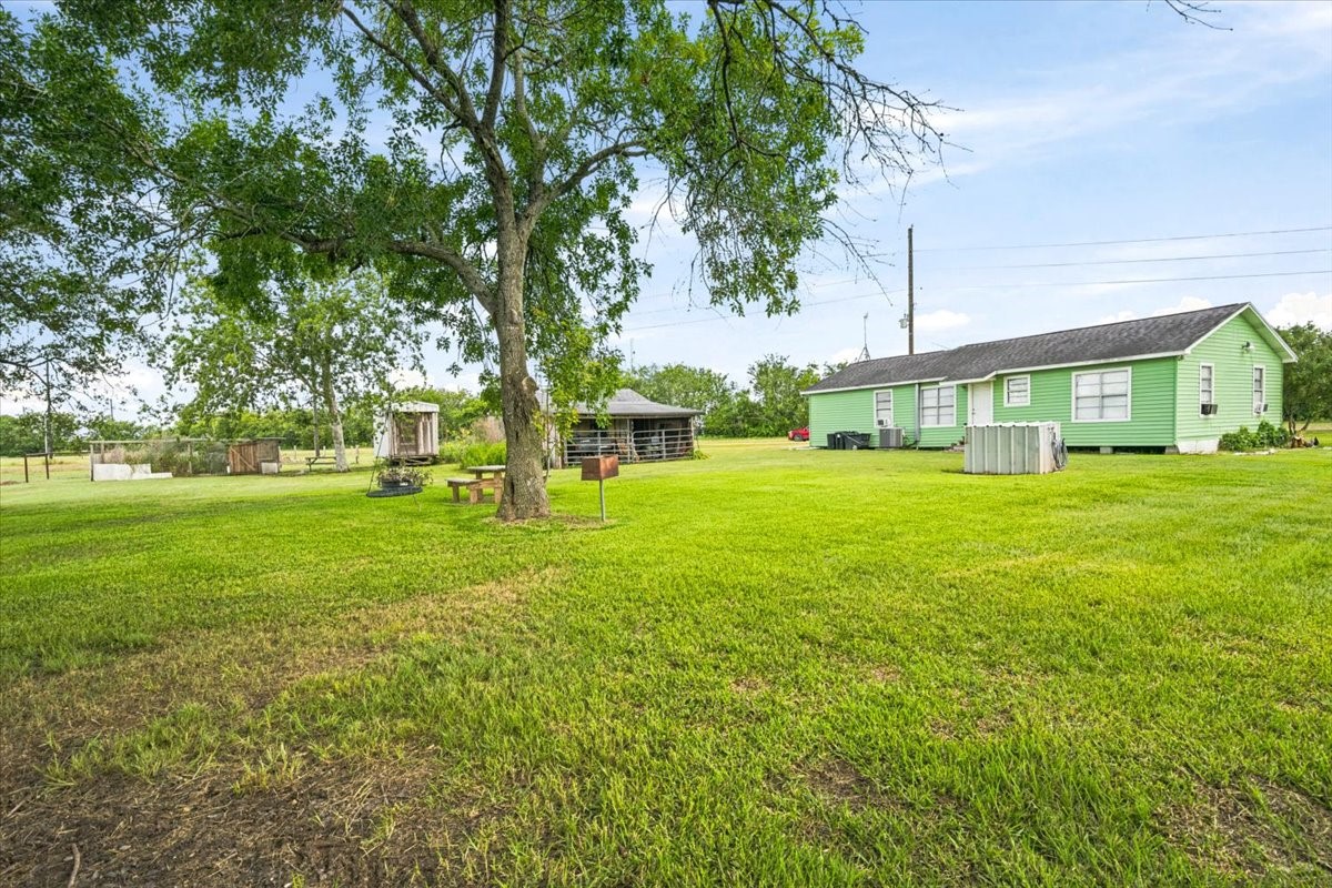 765 Norcross Road Wallis, TX 77485 - Photo 8 of 42 Charming rural property featuring a house with a spacious grassy yard, mature trees, and a few outbuildings. Ideal for those seeking a peaceful, country lifestyle.
