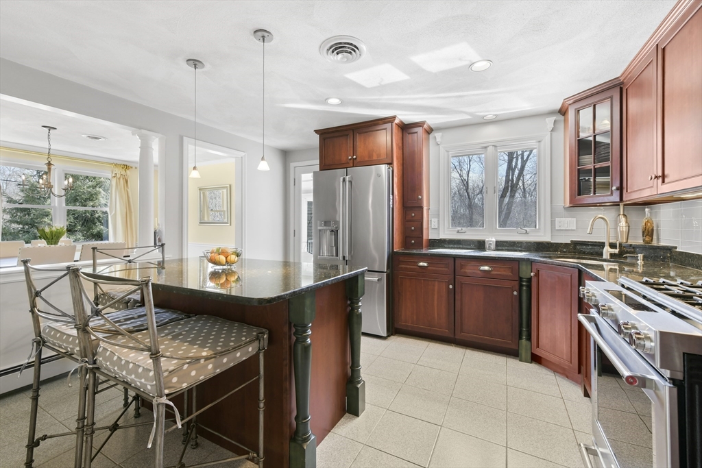 4 Coach Lane Dedham, MA 02026 - Photo 8 of 32 a kitchen with stainless steel appliances granite countertop a stove top oven a sink dishwasher a dining table and chairs with wooden floor