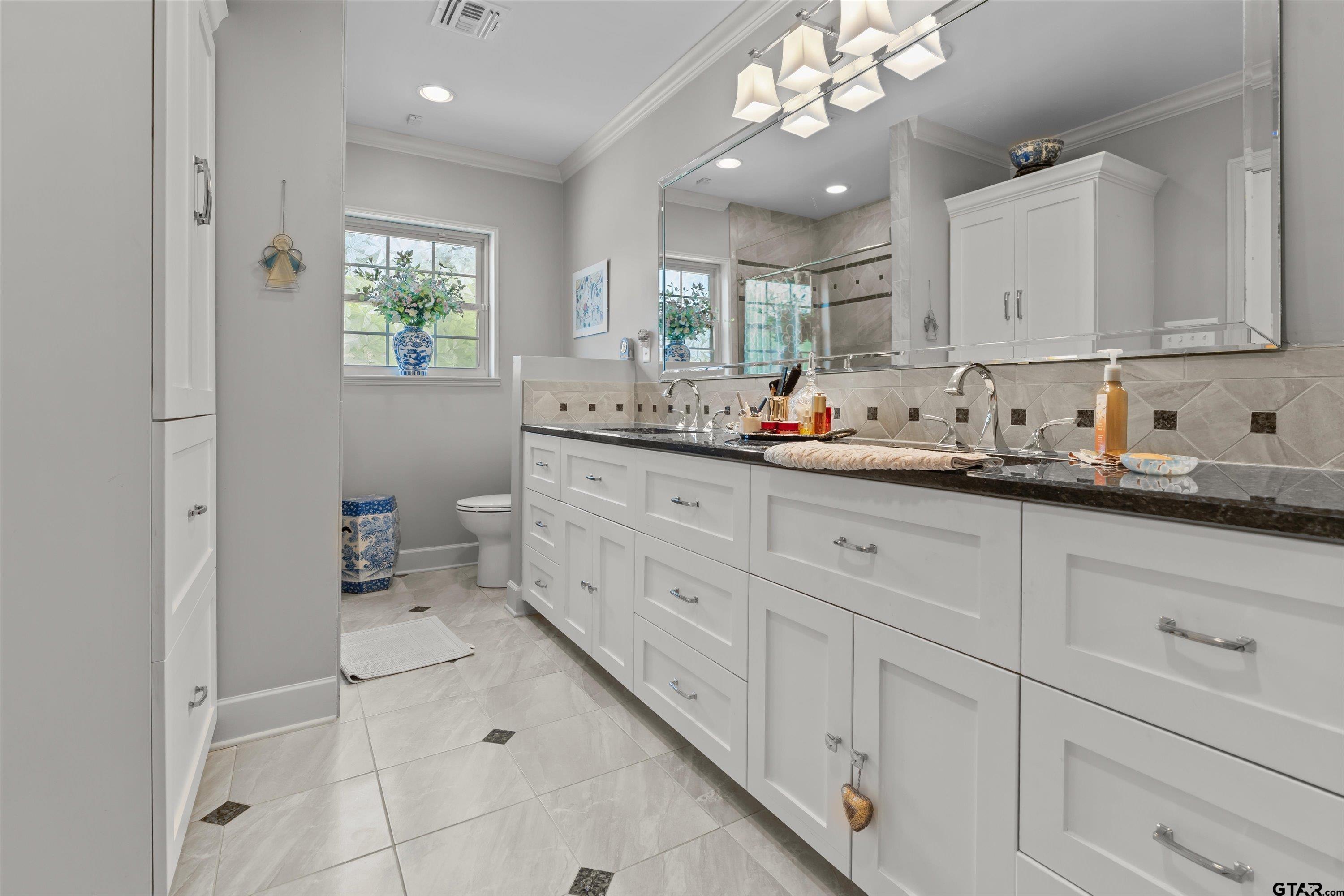 121 Fair Lane Tyler, TX 75701 - Photo 23 of 46 a bathroom with a double vanity sink a mirror and a toilet